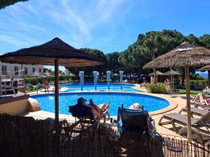 a couple of people sitting in lawn chairs by a pool at 2 bed appartment, close to the beach in Albufeira