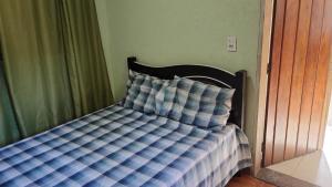 a bed with a blue and white comforter in a bedroom at Cabana centro Pinhal in Santo Antônio do Pinhal