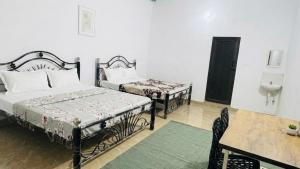 a bedroom with two beds and a table and a sink at Delight rooms in Mysore