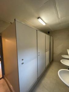 a bathroom with four sinks and stalls with white doors at Vakantiehuis Perles de la cascade in Stavelot