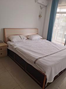 a bed with white sheets and pillows in a bedroom at 海客瀛洲 Haïke-Îlezone in Abidjan