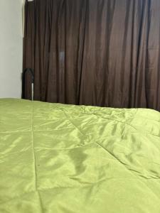 a bed with a yellow comforter in front of a curtain at Green side in Ganja