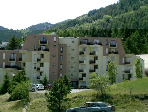 an apartment building with a car parked in a parking lot at Cocon Montagne Vue exceptionnelle Pra-Loup 1500 in Uvernet