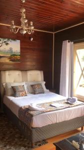a bedroom with a large bed with a chandelier at Pousada requinte serrano in Urubici