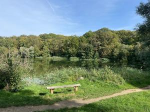 a bench sitting in front of a lake at Le Petit Ekrin des Ursines in Vélizy-Villacoublay