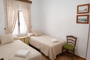 a room with two beds and a chair and a window at Casa Rural la Quinteria de Sancho piscina para tres apartamentos in Argamasilla de Alba +32 photos