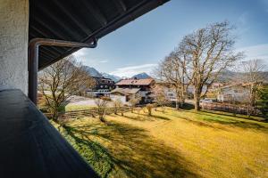 Blick auf einen Garten mit Bäumen und einem Zaun in der Unterkunft Moderne Ferienwohnung mit Ifenblick, Panorama & Parkplatz in Oberstdorf