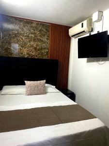 a bedroom with a bed with a tv on the wall at Bahia Suite Alojamiento Centro historico in Santa Marta