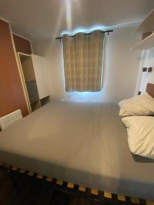 a large white bed in a room with a window at Camping Mayotte, Biscarosse in Biscarrosse