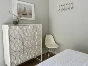 a bedroom with a white dresser and a chair at Ferienwohnung VIER Hof Himmelgrün in Saal