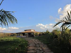 um caminho de pedra que leva a uma casa num campo em Cataguás Brasil Pousada em Carrancas