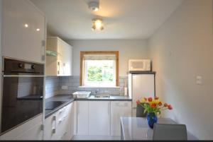 a kitchen with white cabinets and a vase of flowers at Cozy 1 bed flat in Stornoway in Stornoway +3 photos