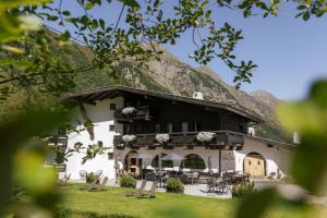 a large white building with a mountain in the background at Natur Residenz Anger Alm - Adults only in Sankt Leonhard im Pitztal