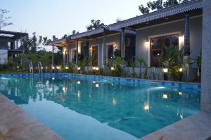 a villa with a swimming pool in front of a house at Eleven Eleven Villa in Pondicherry