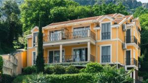 a large yellow house with balconies and trees at Private Terrace Living - Blue Flag Beach & Family Retreat near Kotor in Gornji Orahovac