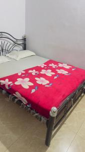 a red blanket with white flowers on a bed at Mysore rooms- sgh in Mysore +8 photos