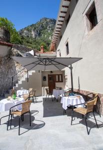 a patio with tables and chairs and an umbrella at Hotel Boutique Las dos Peñas in Mier