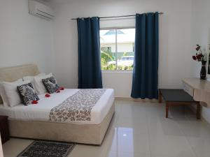 a bedroom with a bed with blue curtains and a window at Blue Sky Self Catering in Grand Anse