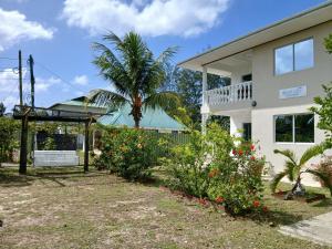 a house with a palm tree and flowers in the yard at Blue Sky Self Catering in Grand Anse