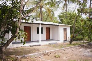 a small white house in the middle of trees at Chandrachhaya Agro Farms Boisar in Boisar +20 photos