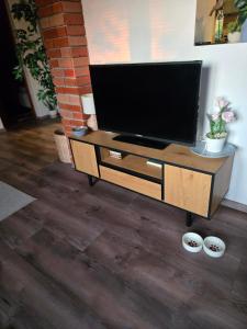a television on a wooden stand in a living room at Maradj Még Vendégház in Balatonakarattya