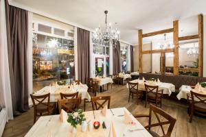 a restaurant with white tables and chairs and a chandelier at Hotel Theophano in Quedlinburg