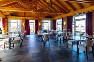 a dining room with tables and chairs and windows at Wirtshaus Feininger Hof in Benz