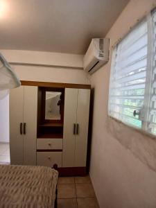 a bedroom with a bed and a window with a air conditioner at Résidence EmiRose in Rivière-Pilote