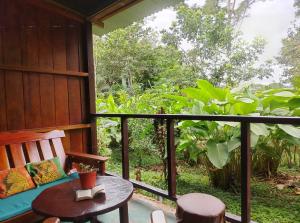 a porch with a table and a chair and a window at Musas Garden Lodge Tambopata in Puerto Maldonado