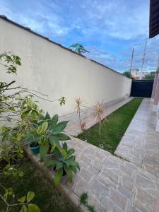 a garden with plants next to a white wall at Brilho do Sol in Guarapari