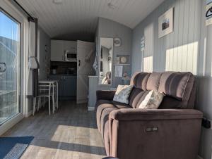 a living room with a couch and a kitchen at Allibella Shepherds Hut, Amazing Seaview, Private garden, Pet Friendly in Barmouth