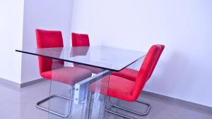 a glass table and red chairs in a room at sempri djuntu T1A in Tarrafal
