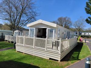 a white house with a porch on the grass at Hoburne Devon Bay - 2 Bed Caravan - Activity Passes Included in Goodrington