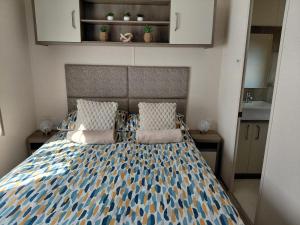 a bedroom with a bed with a blue and white comforter at Hoburne Devon Bay - 2 Bed Caravan - Activity Passes Included in Goodrington +38 photos