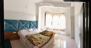 a bedroom with a bed with a blue headboard and a window at Hotel om banna in BhÄdura