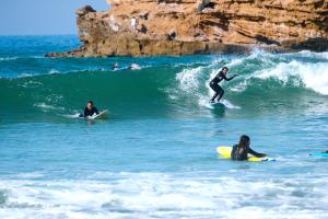 three people riding a wave on surfboards in the ocean at Surf sky tamraght in Agadir