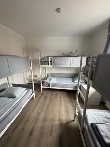 a room with three bunk beds and a wooden floor at Whale House in Keflavík