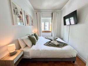 a bedroom with a bed and a tv on the wall at Aura Campo de Ourique - Near the Tram 28 stop in Lisbon