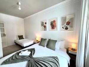 a bedroom with two beds and two tables with lamps at Aura Campo de Ourique - Near the Tram 28 stop in Lisbon