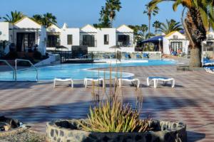 a swimming pool with white chairs and a resort at No & Na Bungalow Montecastillo i1 in Caleta De Fuste