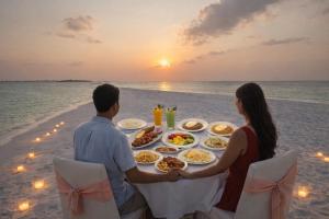 a couple sitting on the beach with a table of food at Aasna Inn in Thulusdhoo