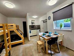 a kitchen and dining room with a table and a bunk bed at Apartmány u Mravence in Starý Petřín