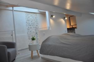 a bedroom with a bed and a chair and a window at Holiday in Arles -Maison du Centre Historique in Arles