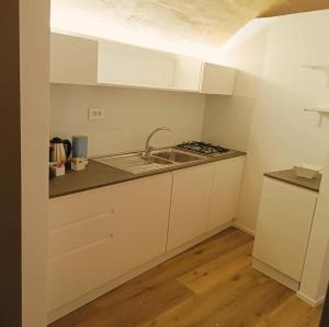 a white kitchen with a sink and a stove at Alma Mater Suite in Matera
