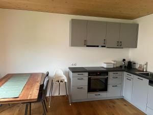a kitchen with white cabinets and a wooden table and a table and a wooden table at Ferienwohnung MARTIN in Göfis