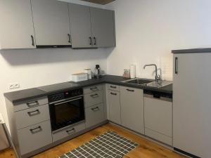 a kitchen with white cabinets and a sink and a stove at Ferienwohnung MARTIN in Göfis +5 photos