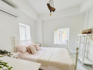 a white bedroom with a bed with pink pillows at Yellow House Kassiopi in Kassiopi