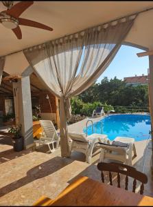 a patio with a pool and chairs and a umbrella at Apartmani Kasteljan 7, Stara novalja in Stara Novalja