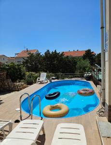 a swimming pool with two chaise lounges and a swimming pool at Apartmani Kasteljan 2, Stara Novalja in Stara Novalja