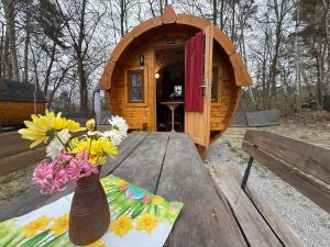 a vase of flowers on a table in front of a tree house at Campingfass Zur Adria in Großdubrau